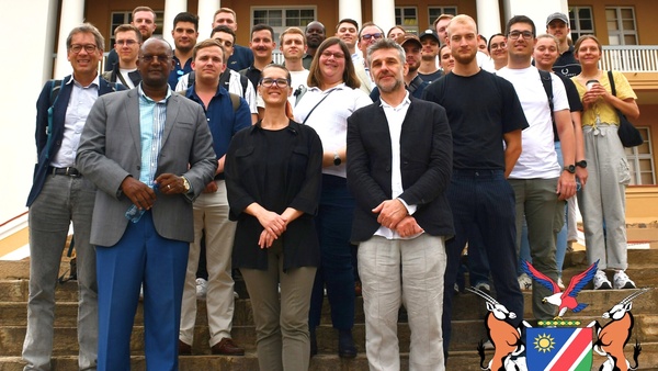 Gruppenfoto der Namibia-Exkursions-Klasse mit zwei Referenten der Konrad-Adenauer-Stiftung vor dem Parlament Namibias