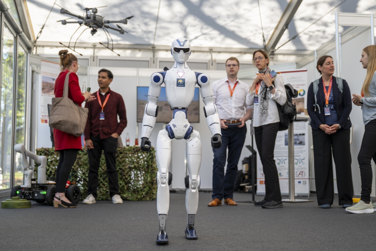 Teilnehmende und ein Roboter auf der Fachausstellung der dtec.bw-Jahrestagung