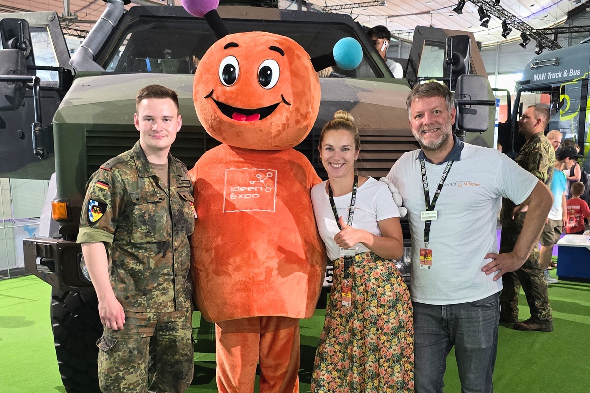 Mitarbeitende der UniBw M zusammen mit dem Maskottchen der IdeenExpo
