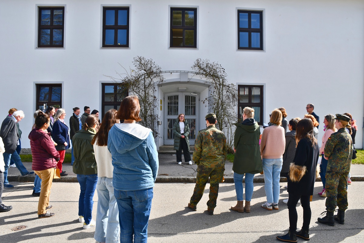 Dr Felicitas Meifert Menhard steht mit dem Rücken zum studium plus Gebäude und vor ihr stehen die Teilnehmenden des Campusrundganges.