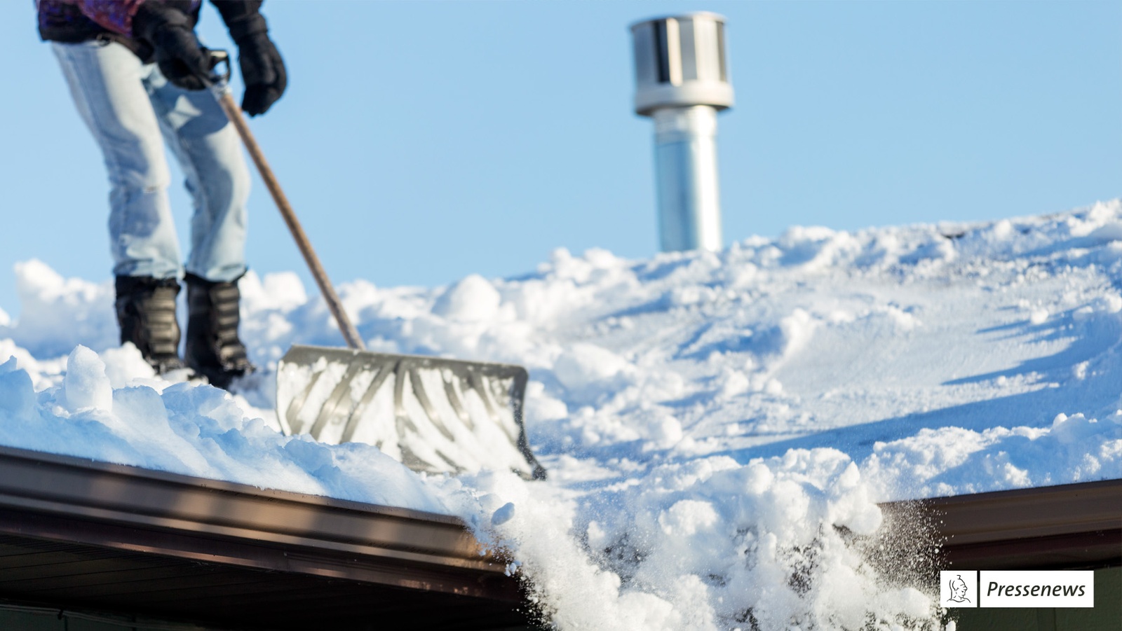 Schnee kann Dachstatik beinträchtigen Foto einer Person die ein Dach von seiner Schneelast befreit