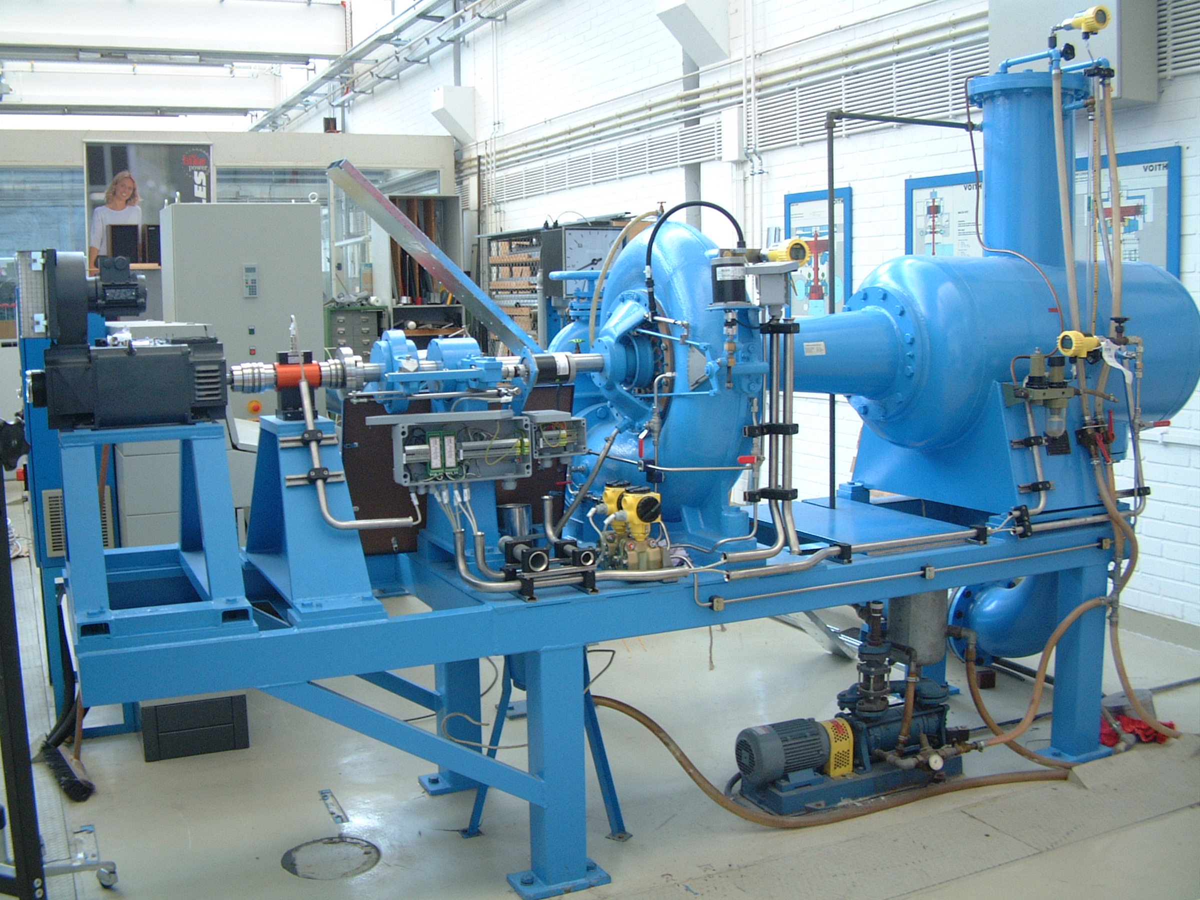 Bei der im Labor für SM vorhandenen Kaplanturbinenanlage kann das Betriebsverhalten einer Modell-Kaplanturbine der Firma Voith untersucht werden. Der am Eintritt in die Turbinenstufe über eine radiale Kreiselpumpe erzeugte Wasserdruck entspricht im Auslegungspunkt der Turbine einer Fallhöhe von H = 6,1 m. Die in der Turbine umgesetzte Energie wird in einem Gleichstrom-Generator in Strom umgewandelt und anschließend ins öffentliche Stromnetz eingespeist.